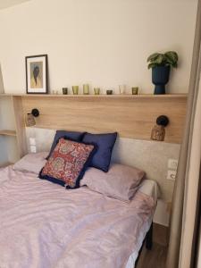 uma cama com uma cabeceira em madeira com uma almofada em Tiny house aan het Zuidlaardermeer - vlakbij Groningen em Kropswolde