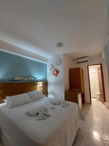 1 dormitorio con 1 cama con sábanas blancas y pared azul en Pousada Lua Azul, en Porto de Galinhas