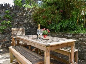 uma mesa de madeira com 2 cadeiras e copos de vinho em The Glen at Ugborough - South Hams Holiday Home em Ugborough