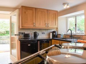 a kitchen with wooden cabinets and a black dishwasher at The Glen at Ugborough - South Hams Holiday Home in Ugborough