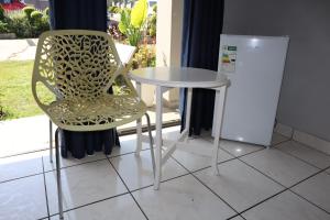 a table and a chair next to a table and a refrigerator at Enhle Bed and Breakfast in KwaDukuza