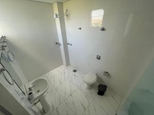 een witte badkamer met een toilet en een wastafel bij Shalom Flat Hotel in Pará de Minas