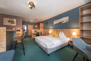 Cette chambre comprend un lit, un bureau et des chaises. dans l'établissement AlpenParks Hotel MONTANA, à Matrei in Osttirol