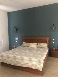 a bedroom with a large bed with a blue wall at NDARI in Siendou