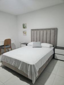 a bedroom with a large white bed and a chair at Hermoso apartamento in Pitalito