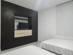1 dormitorio con 1 cama y TV en la pared en Hermoso apartamento, en Pitalito