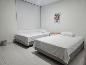 2 camas en una habitación con paredes blancas en Hermoso apartamento, en Pitalito