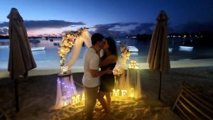 a man and woman kissing under a wedding arch on the beach at Coco Lux Studio Grand Baie in Grand-Baie