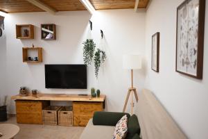 uma sala de estar com televisão numa parede branca em Faliero Room em Canosa di Puglia