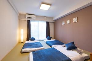 three beds in a room with a window at HOTEL ECCLESIA in Kyoto