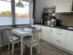 博爾庫姆的住宿－Huus Mövchen，厨房配有白色的桌子和两把椅子