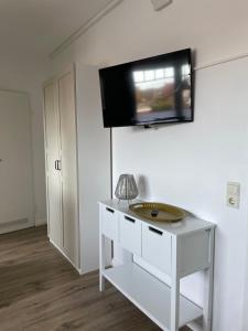 ボルクムにあるHuus Mövchenの白いテーブル、壁掛けテレビが備わる客室です。