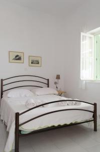 a bedroom with a bed with white sheets and a window at Georgias House in Skiros