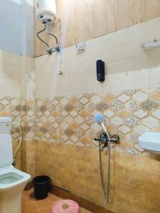 a shower with a hose in a bathroom with a toilet at Metroview rooms & hotel in Bahādurgarh