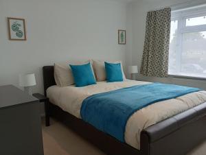 a bedroom with a bed with blue pillows and a window at 3BR House with garden near Bicester Village in Bicester