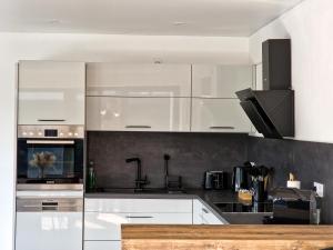 uma cozinha com armários brancos e electrodomésticos de aço inoxidável em Moderne Wohnung in Bad Berleburg em Bad Berleburg