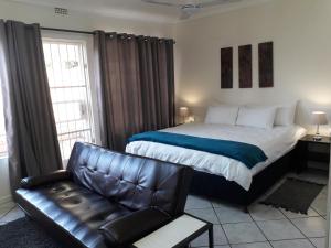 a bedroom with a bed and a leather couch at Protea Park Self Catering Guesthouse in Rustenburg