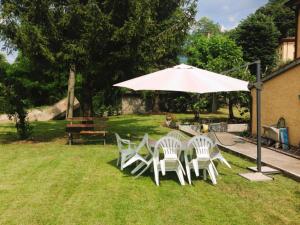 eine Gruppe Stühle und ein Regenschirm im Gras in der Unterkunft La casa del Mike in Borgo a Mozzano