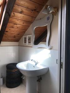 La salle de bains est pourvue d'un lavabo blanc et d'un plafond en bois. dans l'établissement da nonna Emi, à Modène