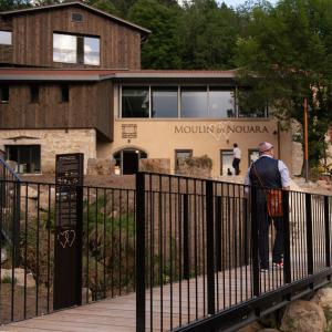 mężczyzna stojący na płocie przed budynkiem w obiekcie Le Moulin de Nouara w mieście Ambert