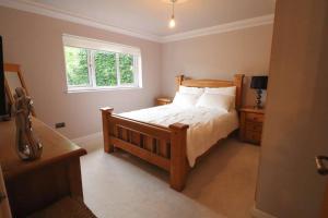 a bedroom with a wooden bed and a window at Woodhead view in Kirkintilloch