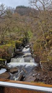 a river with waterfalls on the side of a road at The Abbotsford in Callander