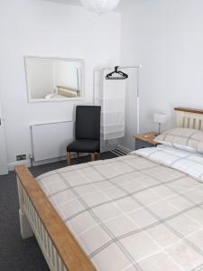 1 Schlafzimmer mit 2 Betten und einem schwarzen Stuhl in der Unterkunft Cape Cottage in Glyncorrwg