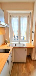 a kitchen with a sink and two windows at MarTina's Home GRIS in Alba