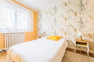 ein Schlafzimmer mit einem weißen Bett und einer Blumenwand in der Unterkunft Les Rosiers - Maison avec JACUZZI in Brive-la-Gaillarde
