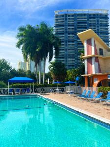 a swimming pool with chairs and palm trees and a building at Bposhtels Hollywood Florida in Hollywood