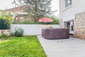 an umbrella and a table with a chair under it at Les Rosiers - Maison avec JACUZZI in Brive-la-Gaillarde