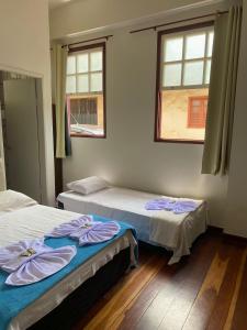 two beds in a room with two windows at Casa do Alferes in Ouro Preto