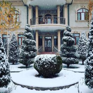 una casa cubierta de nieve con árboles delante en Mavie Guest House, en Tashkent