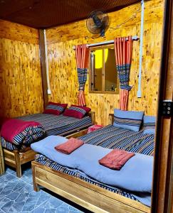 twee bedden in een kamer met houten wanden bij Pura Homestay in Na Thôn