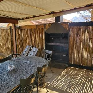 a patio with a table and chairs and a grill at Walkers Peak Cottage in Underberg