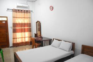 a bedroom with two beds and a table and a window at Green Mart Family Rest in Anuradhapura