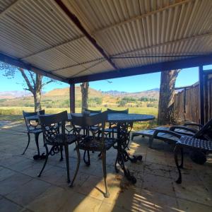 a table and chairs on a patio with a view at Walkers Peak Cottage in Underberg