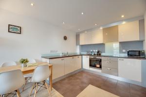 a kitchen with white cabinets and a table and chairs at All Saints Apartments 705 by Week2Week in Newcastle upon Tyne