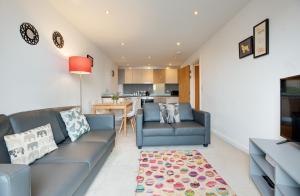 a living room with two blue couches and a kitchen at All Saints Apartments 705 by Week2Week in Newcastle upon Tyne