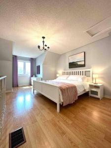 a bedroom with a white bed and a wooden floor at Charming Home in Prime Location North of Toronto in Richmond Hill