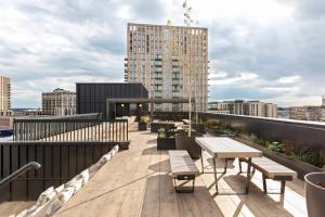 una terraza en la azotea con mesas y bancos en un edificio en ARK Wembley, en Londres