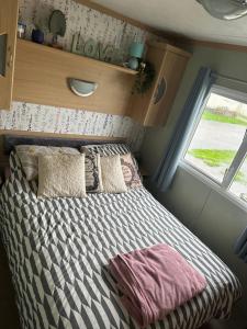 Ce lit se trouve dans une petite chambre dotée d'une fenêtre. dans l'établissement Robin Hood Rhyl caravan oaklands, à Rhyl