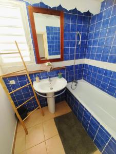 uma casa de banho em azulejos azuis com um lavatório e uma banheira em les Aliceas appartement cosy em Baie-Mahault