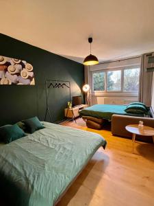 a bedroom with two beds and a green wall at Le Roland-Garros in Chalon-sur-Saône