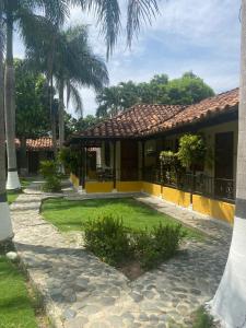 a house with a courtyard with palm trees at Hotel Campo Campestre La Coqueta in Santa Fe de Antioquia