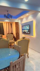 een woonkamer met een tafel en stoelen en een televisie bij Luxury Stay at Mokktam Heights in Caïro