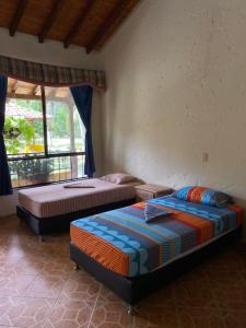 two beds sitting in a room with a window at Hotel Campo Campestre La Coqueta in Santa Fe de Antioquia