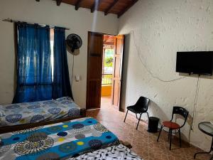 a bedroom with a bed and two chairs and a television at Hotel Campo Campestre La Coqueta in Santa Fe de Antioquia