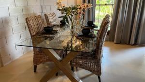 a dining room table with wicker chairs and a glass tableablish at Thatchwood Cottage in Hilton