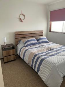 a bedroom with a bed with blue and white stripes at Cómoda y amplía casa con Quincho in Punta Arenas